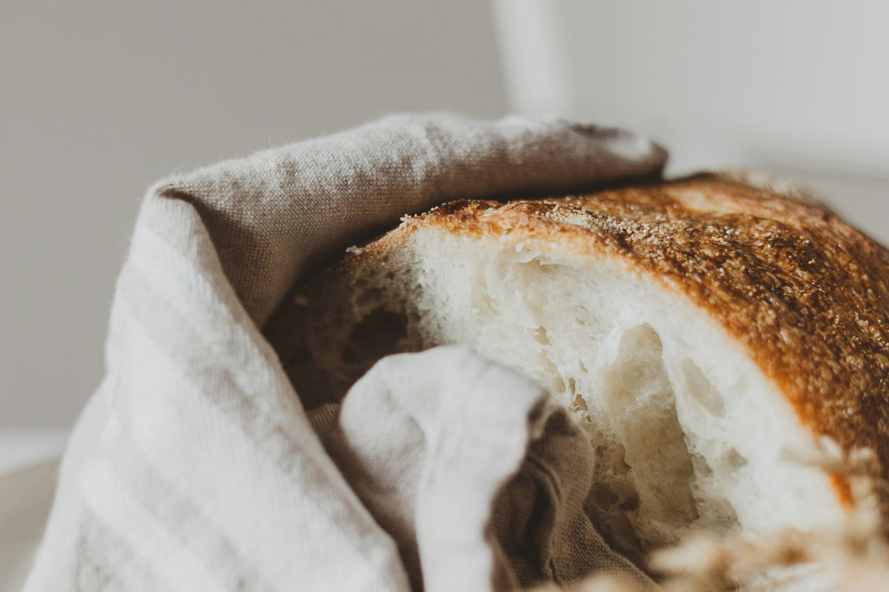 A crusty round loaf wrapped in natural linen.